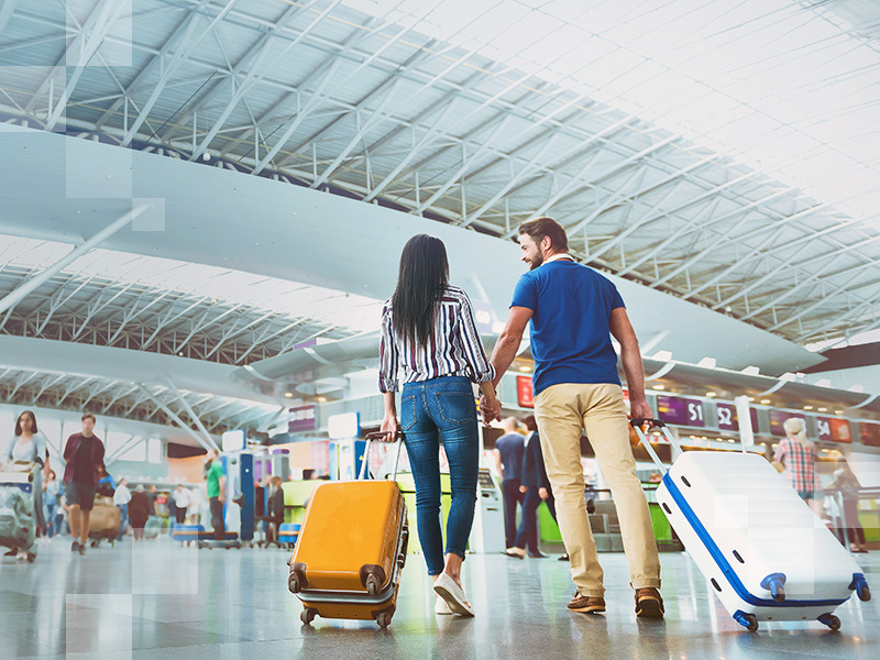 Cheerful passengers are holding hands and carrying their luggage. They walking to terminals. Low angle. Copy space