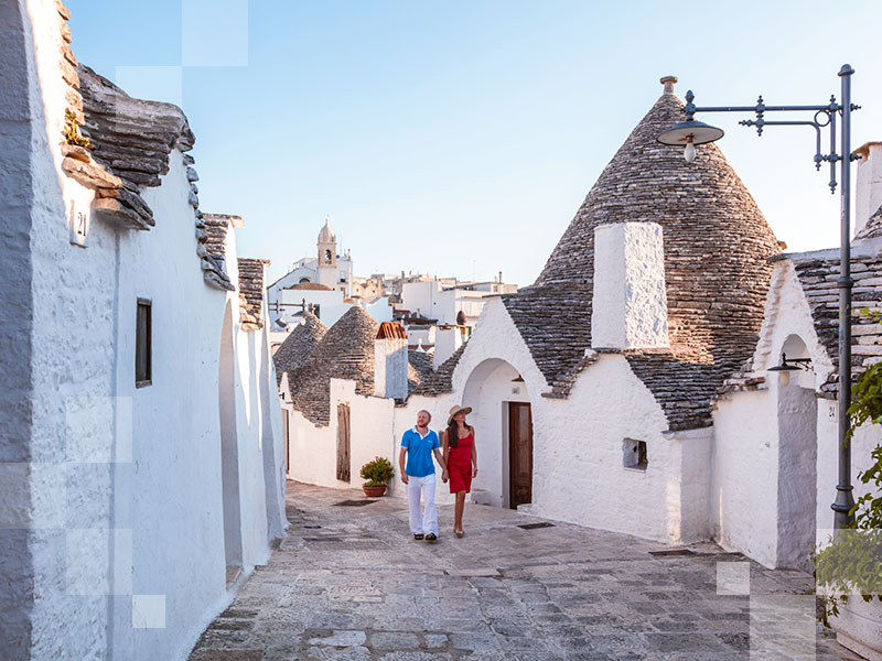 Tourist couple visiting the Trulli area, Alberobello, Itria valley, Apulia, Italy  (MR)